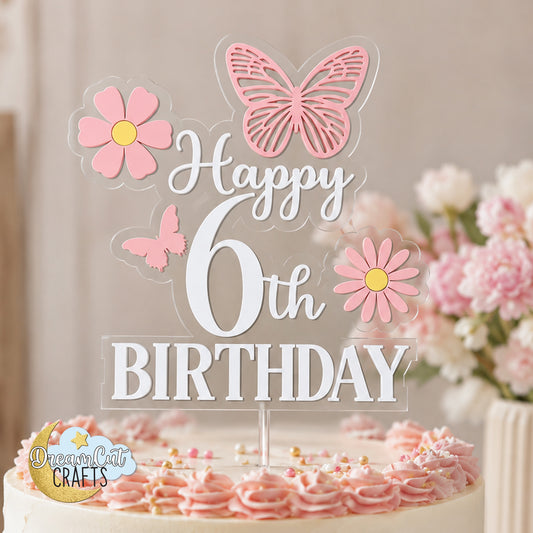 Layered acrylic birthday cake topper with custom age, white Happy Birthday lettering, pink butterflies and pink daisies attached to a clear acrylic base.