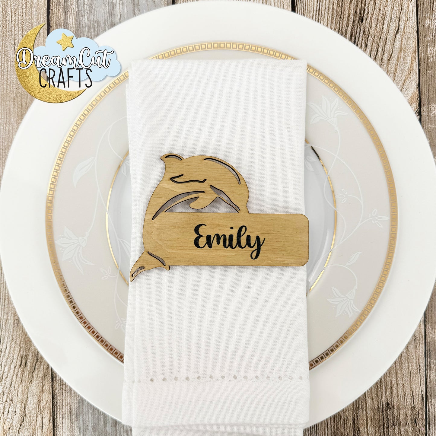 Wooden wedding place card with a custom name engraved on a white napkin over a white plate.