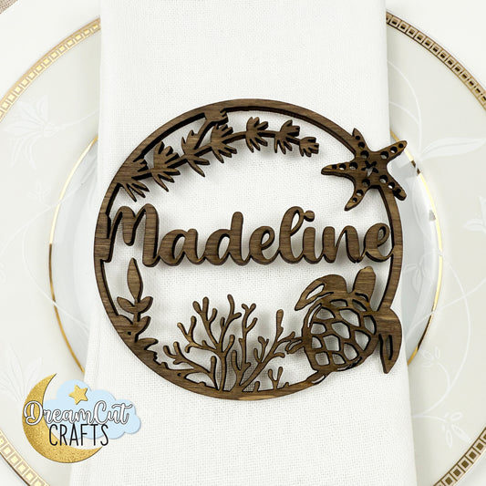 Sea-themed personalized name place card with script name on round base featuring sea turtle, starfish and coral design.